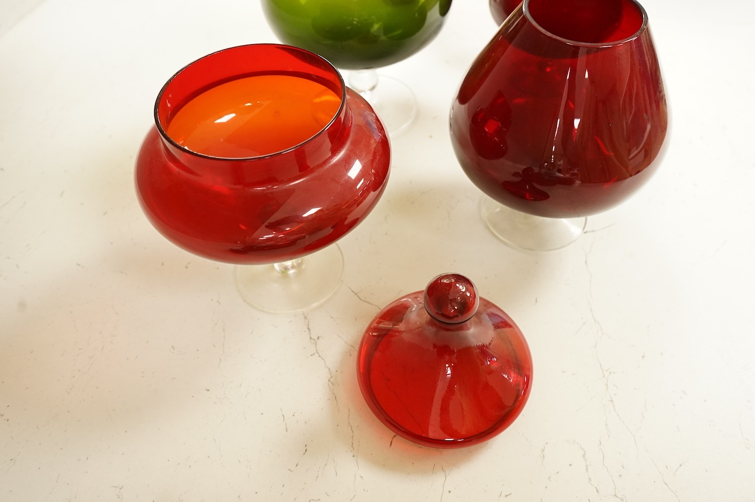 Five pieces of glassware to include a Swedish oversized brandy balloon, red glass sweetmeat dish and cover and a vase, largest 28cm high